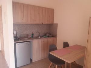 a kitchen with wooden cabinets and a table with chairs at Nereids Apartments-Erato in Petalidi
