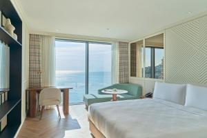 a hotel room with a bed and a desk and a window at Grand Josun Busan in Busan