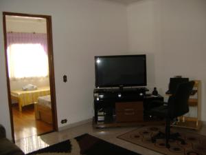 sala de estar con TV de pantalla plana y silla en Apartamento Guarulhos, en Guarulhos
