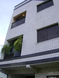un edificio blanco alto con plantas en las ventanas en Apartamento Guarulhos, en Guarulhos