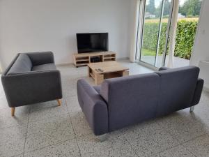 a living room with two chairs and a couch and a tv at Villa 2 luxe in Fresney-le-Vieux