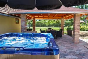 a hot tub on a patio with an umbrella at Levendulás Tanya Szarvas - Jakuzzi és medence in Szarvas