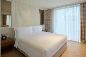 a bedroom with a large white bed and a window at Grand Josun Busan in Busan