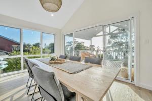 a dining room with a table and chairs and windows at Beach House on Bentley in Bridport