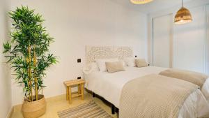 a white bedroom with a bed and a plant at Tinajas Chic in Corralejo +42 photos