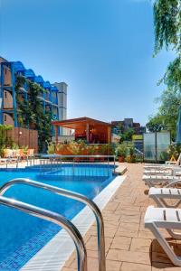 una piscina con tumbonas y un edificio en Paloma Hotel, en Sunny Beach