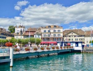 un ponte su un corpo idrico con edifici di Hotel Le Rive a Nyon