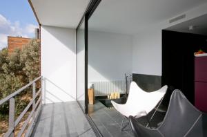 ein Balkon mit zwei weißen Stühlen und Glaswänden in der Unterkunft Consolación in Monroyo