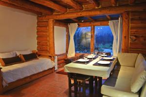 sala de estar con mesa, cama y ventana en La Campiña en San Carlos de Bariloche