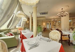 un restaurante con mesas y sillas blancas y lámparas de araña en SPA-HOTEL PLAZA Essentuki, en Yessentuki