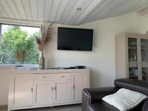 uma sala de estar com uma televisão na parede em Chalet des Campanules avec Sauna em Vielsalm