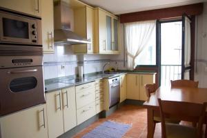 a kitchen with white cabinets and a table and a microwave at Piso Céntrico con Terraza y Garaje Para Tu Familia in Baiona