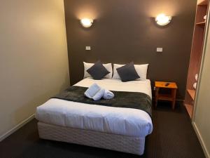 
a white bed with a white comforter and pillows at The Astor Hotel Motel in Goulburn
