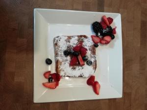 a piece of cake with fruit on a white plate at Bed and Breakfast Bianca in Standdaarbuiten