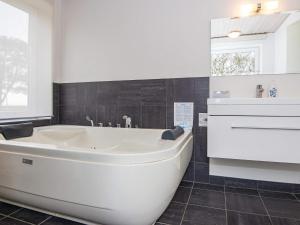 uma banheira branca na casa de banho com um lavatório em 10 person holiday home in R m em Bolilmark