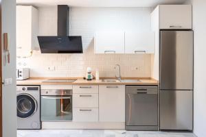 a kitchen with white cabinets and a stainless steel refrigerator at Apartamento AGUASAL in Sanlúcar de Barrameda