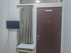 een kamer met een deur, een stoel en een lamp bij Colombus Residence Karawang Mitra RedDoorz in Telukjambe