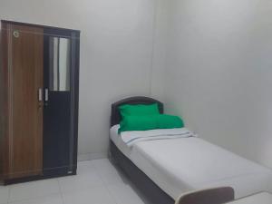 een klein bed in een kamer met een groen kussen bij Colombus Residence Karawang Mitra RedDoorz in Telukjambe