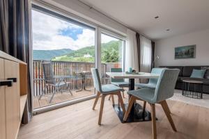 sala de estar con mesa, sillas y ventana grande en Lapis Monti - Apartments & Suites, en Burgusio