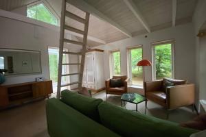 un soggiorno con divano verde e scala a pioli di Oak Cottage near Rønne & Beach a Rønne