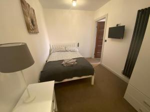 a small bedroom with a bed and a lamp at Clover Cottage in Beeley