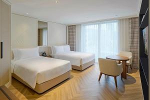 a hotel room with two beds and a table at Grand Josun Busan in Busan