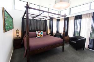 Starhaven Retreat في بورترلينجتون: غرفة نوم بسرير مظلة وكرسيين