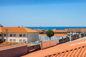 a view of roofs of buildings with the ocean in the background at Espinho Sunshine Flat in Espinho