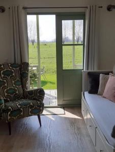 a bedroom with a bed and a chair and a window at Roulotte Hartemeers in Tielt