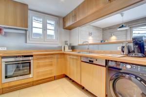 cocina con armarios de madera, lavadora y secadora en Les Gravillons, en Morzine 14 fotos más