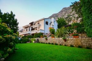 a house with a stone wall and a green yard at Djardin in Kotor