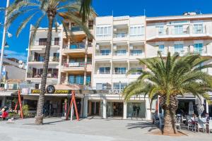 a large white building with palm trees in front of it at Hostal Vista Alegre in Port d'Alcudia