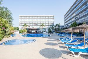 una piscina con sillas y sombrillas y un hotel en Sol Costa Daurada en Salou