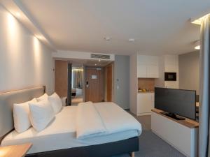 a bedroom with a white bed and a flat screen tv at Holiday Inn Express - Offenbach, an IHG Hotel in Offenbach
