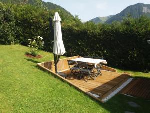 une terrasse en bois avec une table et un parasol dans l'établissement Appartement 2 pièces cuisine Les Hermines, à Saint-Nicolas-la-Chapelle