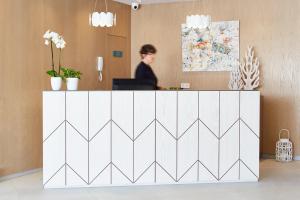 a woman is standing behind a white reception desk at Universal Aparthotel Elisa in Playa de Muro +55 photos