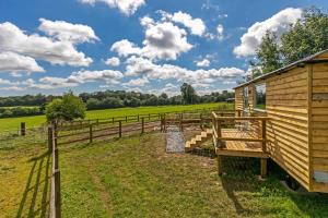 a wooden trailer in a field next to a fence at Jabba, The Hut in Winchester