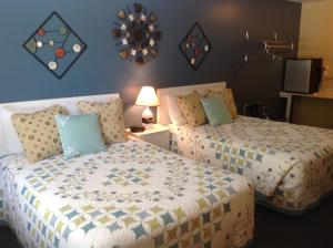 a bedroom with two beds and a clock on the wall at Schooner Bay Motor Inn in Rockport