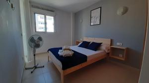 a bedroom with a bed with blue pillows and a fan at Toros Apartamentos in Palma de Mallorca