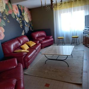Sala de estar con sofás de cuero rojo y mesa de centro en chez cadet, en Larzicourt
