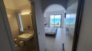 a bathroom with a sink and a room with a bed at Stella Beach Hotel in Panormos Rethymno
