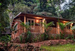 uma cabana na floresta com um alpendre e um deque em Nirvana Hill Resort em Curtorim