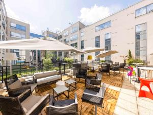 an outdoor patio with chairs and tables and umbrellas at Mercure Paris Massy Gare TGV in Massy
