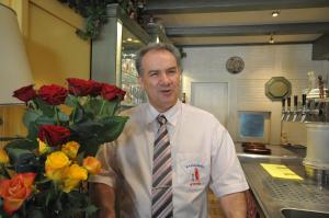 un homme dans une cuisine avec un bouquet de roses dans l'établissement Hotel Restaurant "Athen", à Münstermaifeld