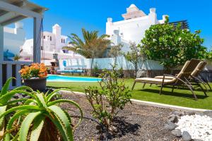 a garden with a chair and a pool at Villa Simba in Corralejo
