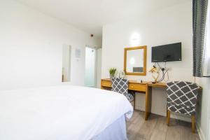 a bedroom with a bed and a desk with a television at The Residence @ Jaipur in Easingwold