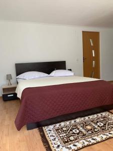 - une chambre avec un grand lit et un tapis au sol dans l'établissement Casa din Grădină, à Moieciu de Jos