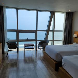 釜山にあるMS ホテル ヘウンデのベッド、テーブル、椅子が備わるホテルルームです。