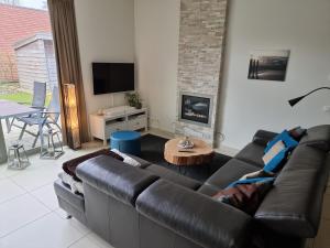 sala de estar con sofá de cuero y chimenea en BONNIES Beach & Spa DuinNest, en Cadzand-Bad