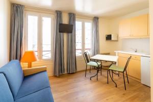 - un salon avec un canapé bleu, une table et des chaises dans l'établissement Hôtel Capfun Le Saint Germain, Paris, à Paris
